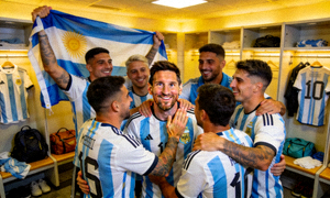 阿根廷国家队球员在更衣室庆祝胜利，梅西在中间微笑